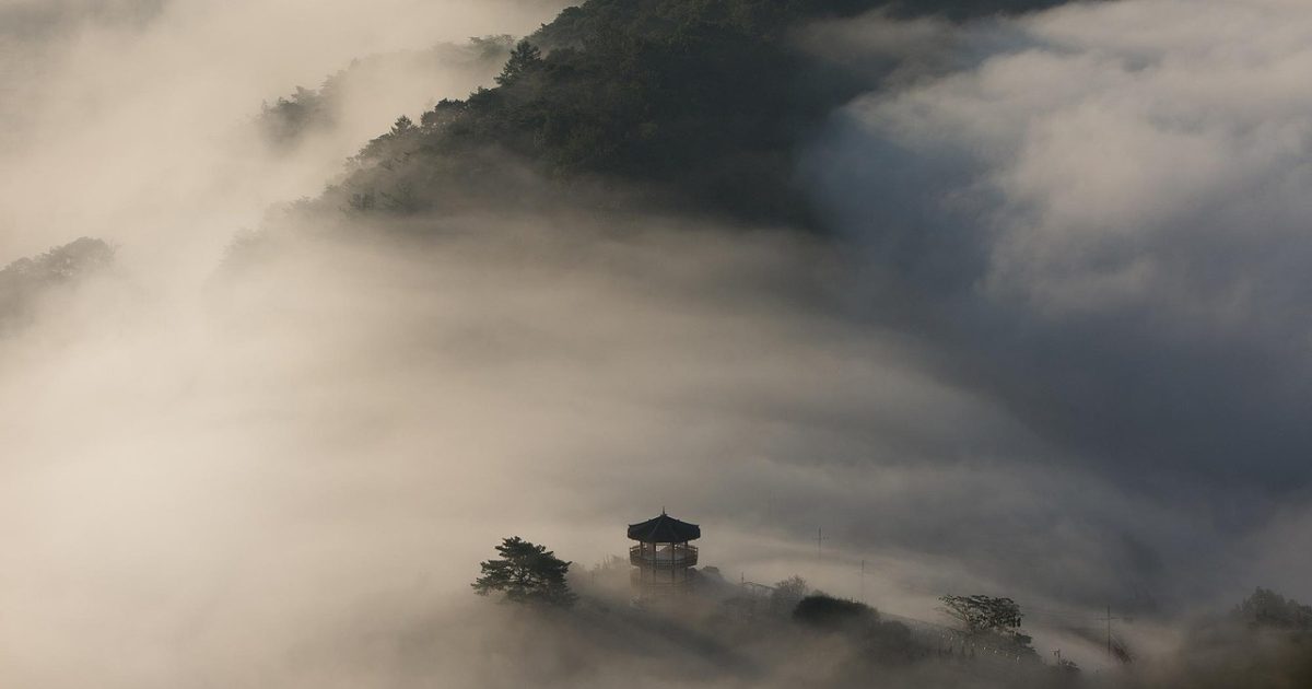 海拔高度查询 App 主界面在清晨山脊上显示实时海拔数字，背景是翻涌云海与远处雪线，屏幕反光映出登山者手套