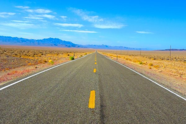 高原公路垭口处的经幡与路牌，自驾车辆停在路边，驾驶员查看实时海拔高度查询读数，天空湛蓝